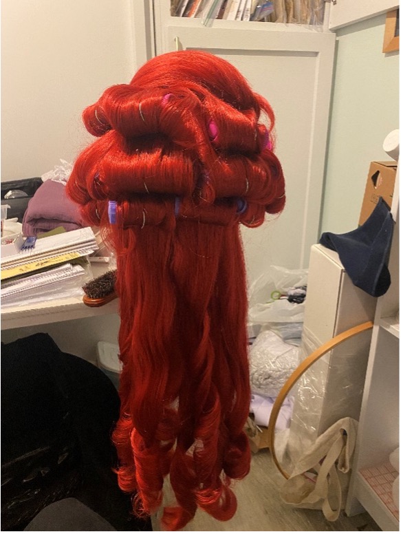 Photo of the wig in curlers on a head form.