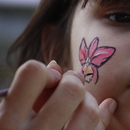 Painting an orchid on a child's cheek